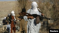 FILE - Taliban fighters carry weapons in an undisclosed location in Nangarhar province.