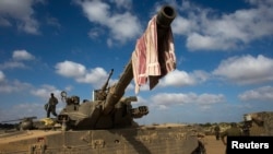 An Israeli soldier stands on a tank outside the northern Gaza Strip, July 26, 2014. 