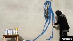 Afghan artist Malina Suliman paints graffiti on a wall in Kandahar city December 30, 2012.