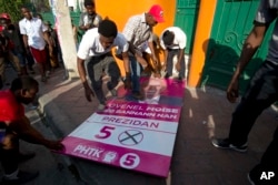 Supporters of presidential candidate Maryse Narcisse, from the Lavalas party, step on a campaign poster of presidential candidate Jovenel Moise, as they protest election results in Petion-Ville, Haiti, Nov. 12, 2015.