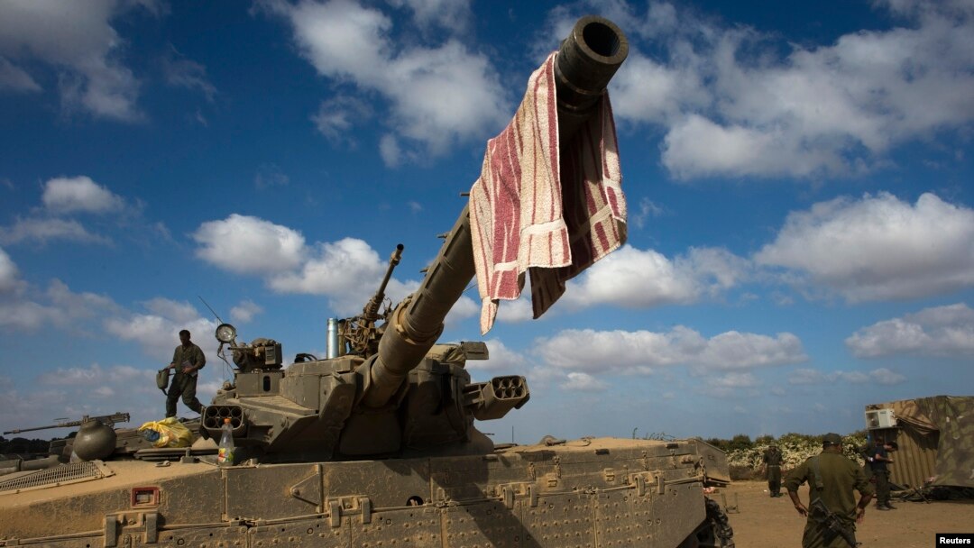 An Israeli soldier stands on a tank outside the northern Gaza Strip, July 26, 2014. 