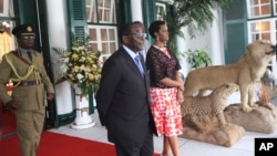 FILE: Zimbabwean President Robert Mugabe, center, and his wife Grace stand at State House in Harare, Saturday, Jan., 23, 2016. Mugabe,91, who was rumored to be sick and hospitalized, returned from his annual vacation on Friday. (AP Photo/Tsvangirayi Mukwazhi)