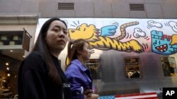 FILE - Women pass by a U.S. fashion apparel store in Beijing, China, May 6, 2019.