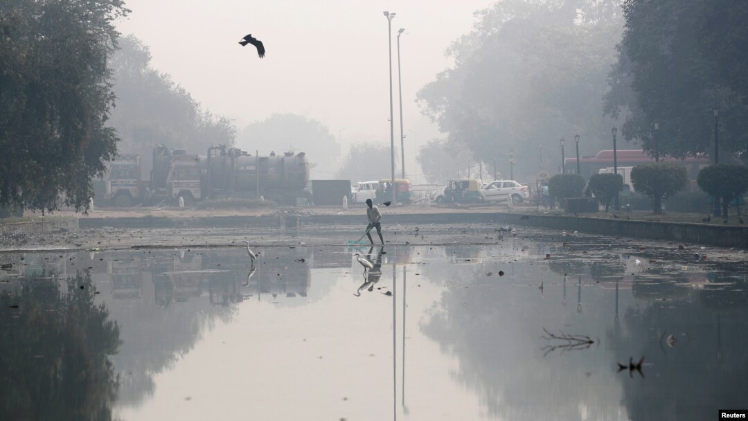 Seorang pria tengah membersihkan kolam di pagi yang berasap di New Delhi, India, 11 November 2019. (Foto: dok).