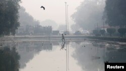 Seorang pria tengah membersihkan kolam di pagi yang berasap di New Delhi, India, 11 November 2019. (Foto: dok).