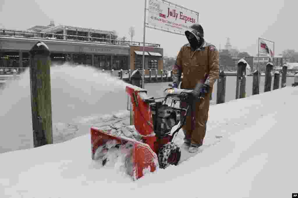 Tony Savage, que trabaja para la ciudad de Annapolis, limpia la nieve a lo largo del City Dock en Annapolis, Maryland.