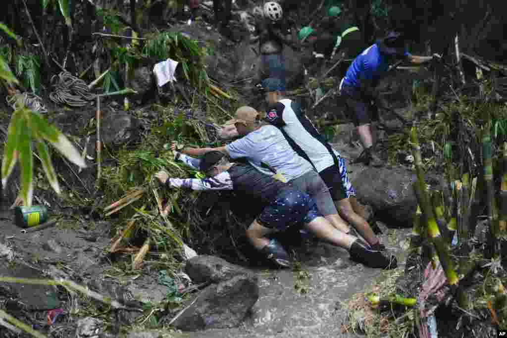 Volunteers and rescuers move debris as they search for bodies of missing residents believed to be buried under a landslide caused by heavy rains from Tropical Storm Yagi, in San Luis village, Antipolo city, Rizal province, Philippines.