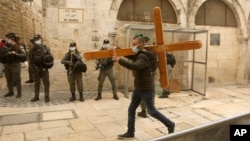 A man carries a cross along the Via Dolorosa ahead of the Good Friday procession towards the Church of the Holy Sepulchre, traditionally believed by many to be the site of the crucifixion of Jesus Christ, in Jerusalem's Old City, April 2, 2021.