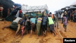 Rohingya refugees pushing a truck that is stuck in mud after heavy rain at Kutupalong camp in Cox's Bazar, Bangladesh, July 4, 2018.