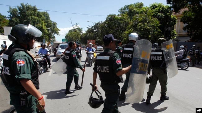 Cambodian riot police officers walk towards workers gathering in front of National Assembly in Phnom Penh, Cambodia, Tuesday, June 30, 2015.