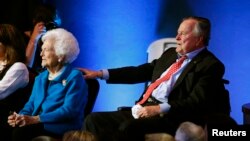 File - Former U.S. President George H.W. Bush reaches out to his wife, former first lady Barbara Bush, as they await the start of Republican presidential candidate debate in Houston, Texas, Feb. 25, 2016.