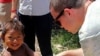 A student, at the University of Georgian’s journalism, shakes hand with a Cambodian child while in the country. 