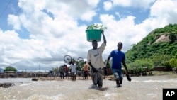 People cross a river with their belongings where a bridge once stood in Phaloni, Malawi, Jan. 22, 2015. 