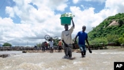 People cross a river with their belongings where a bridge once stood in Phaloni, Southern Malawi, Jan 22, 2015. 