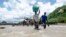 FILE - People cross a river with their belongings where a bridge once stood in Phaloni, Southern Malawi, Jan 22, 2015. 