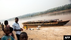 Des gens se tiennent à côté d'un bateau vide sur le Kasaï au port de Tshikapa, en République démocratique du Congo, le 28 juillet 2017.