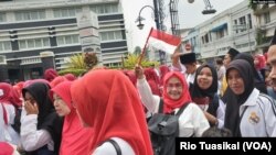 Berbagai kelompok agama memeriahkan parade "Bandung Rumah Bersama" yang digelar Sabtu, 15 Februari 2020. Nampak kelompok muslimah berkerudung dengan tema merah putih membawa bendera. (Foto: RIo Tuasikal/VOA)