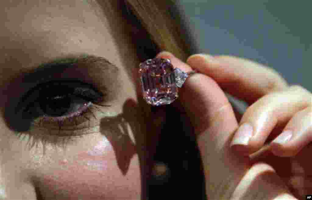 An employee of Sotheby's auction house holding a 24.78 carat fancy intense pink diamond mounted as a ring, that was last seen on the market some 60 years ago, ahead of an upcoming auction in central London. The rare emerald-cut pink diamond is estimated 