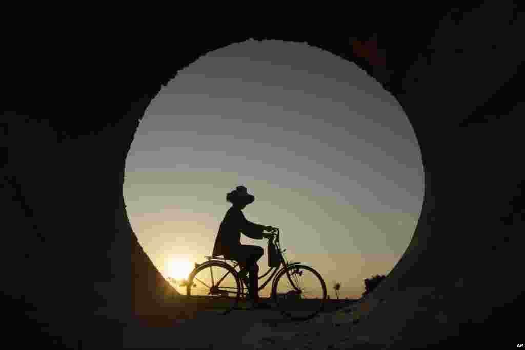 A builder rides a bicycle to work in Samroang village outside Phnom Penh, Cambodia.