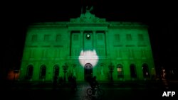 FILE - The City Hall of Barcelona is illuminated in green in support of the Paris climate accord aiming to meet greenhouse gas emission targets, in Barcelona, Spain, June 2, 2017.