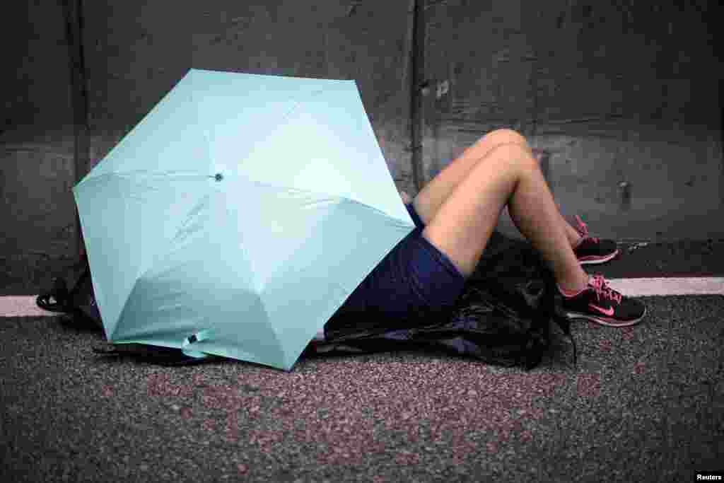 A protester sleeps under an umbrella on a street outside the government headquarters in Hong Kong, Oct. 2, 2014. 