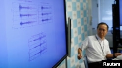 FILE - Japan Meteorological Agency's earthquake and tsunami observations division director Toshiyuki Matsumori speaks next to a monitor showing graphs of ground motion during a news conference at the agency, in Tokyo, Japan, Sept. 3, 2017.