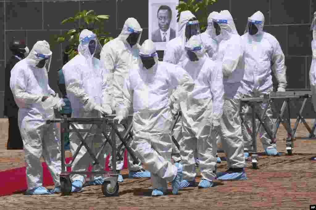 Pallbearers wait for the coffins to arrive at a state burial of government ministers who died of COVID-19, in Harare, Zimbabwe. President Emmerson Mnangagwa, who presided over the burial, called the pandemic &quot;evil&quot; and urged people to wear masks, keep distance and wash their hands.