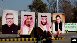 Pakistani riders drive past portraits of Pakistani and Saudi leaders displayed in Islamabad, Pakistan, Feb. 15, 2019. 