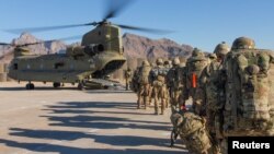 FILE - Soldiers attached to the 101st Resolute Support Sustainment Brigade, Iowa National Guard and 10th Mountain, 2-14 Infantry Battalion load onto a Chinook helicopter to head out on a mission in Afghanistan, Jan. 15, 2019.