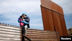 Migrants from Honduras, part of a caravan of thousands from Central America trying to reach the United States, jump onto a border fence to cross illegally from Mexico to the U.S., in Tijuana, Mexico, Dec. 12, 2018. 