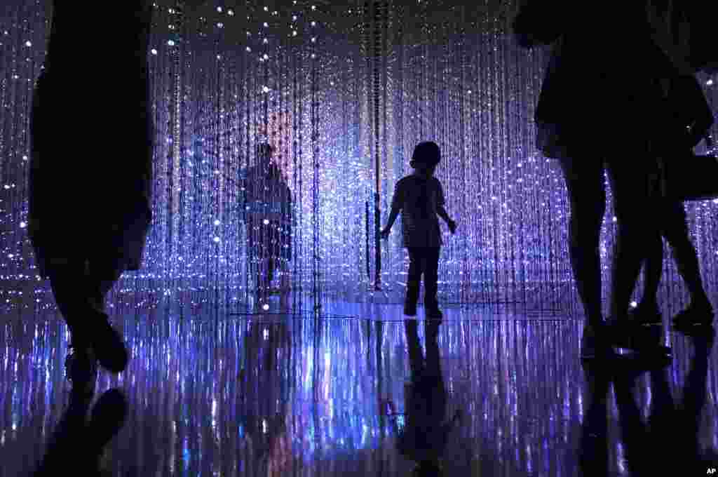 A young boy is seen in silhouette as he walks through a light installation in Singapore.