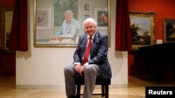 FILE - David Attenborough poses next to a portrait of himself by Bryan Organ to mark his 90th birthday at New Walk Museum and Art Gallery in Leicester, Britain, Sept. 22, 2016.