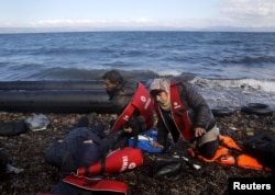 Syrian refugees lie exhausted moments after arriving by a raft at a beach on the Greek island of Lesbos, Oct. 25, 2015.