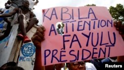 Supporters of the runner-up in Democratic Republic of Congo's presidential election, Martin Fayulu, hold up a sign ahead of a political rally in Kinshasa, DRC, Jan. 11, 2019.