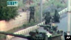 Soldiers take up position near a tank on a street in a location given as Daraa on April 25, 2011, in this still image taken from an amateur video.