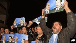 Angry Sunni protesters react as they hold posters showing the slain former prime minister Rafik Hariri, and his son Saad Hariri, who they support, in the southern port city of Sidon, Lebanon, 24 Jan 2011