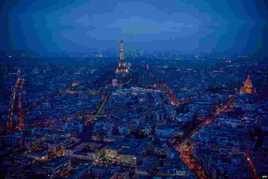 This general view taken from the rooftop of The Tour Montparnasse at twilight, shows The Eiffel Tower (C) and The Dome des Invalides (R) in Paris, France.