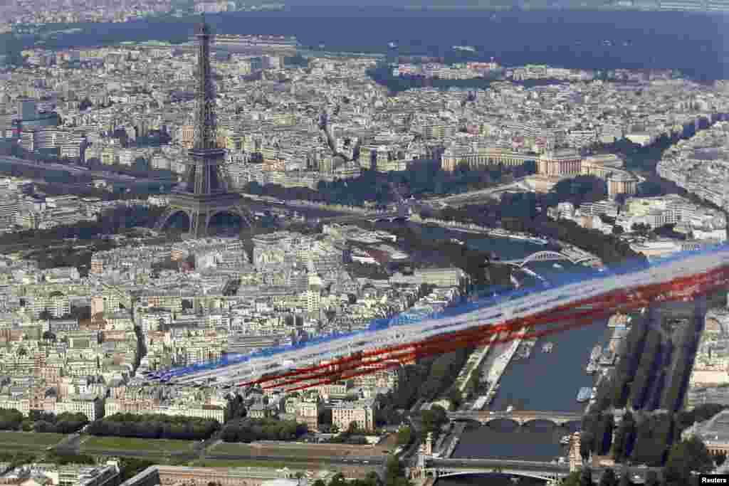 A French aerial display team flies in front of the Eiffel tower as part of the traditional Bastille day military parade, in Paris, July 14, 2013.