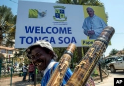 Seorang pedagang kaki lima melewati poster Paus di Antananarivo, Selasa, 3 September 2019.