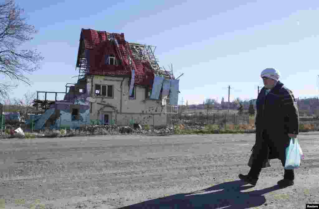 Seorang perempuan berjalan dekat rumah yang hancur karena adu tembak di desa Semyonovka, dekat Slovyansk, Ukraina timur (27/10).&nbsp;(Reuters/Vasily Fedosenko) 