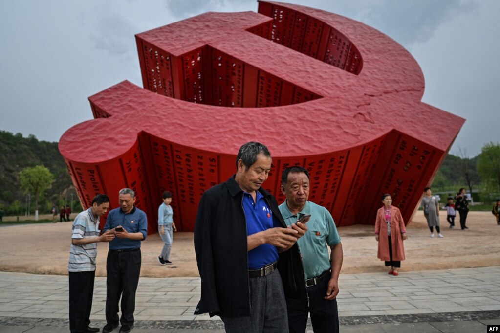 中国民众在延安附近的南泥湾树立的中共镰刀斧子党徽雕塑前拍照。（2021年5月11日）(photo:VOA)