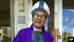 FILE - A Nov. 2014 photo shows Archbishop Anthony Apuron standing in front of the Dulce Nombre de Maria Cathedral Basilica in Hagatna, Guam. Apuron faces multiple allegations of sex abuse of altar boys in the 1970s. He has denied the claims.