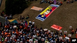 Partidarios del líder de la oposición encarcelado Leopoldo López, llevan carteles que dicen "No más dictadura" cerca de una bandera de López durante un mitin en Caracas, Venezuela, el sábado 18 de febrero de 2017.