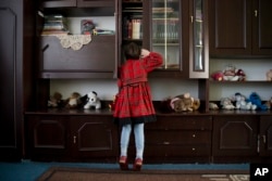 Veronika peers into a cupboard at a children's home in Khartsyzk, Ukraine, March 7, 2015.