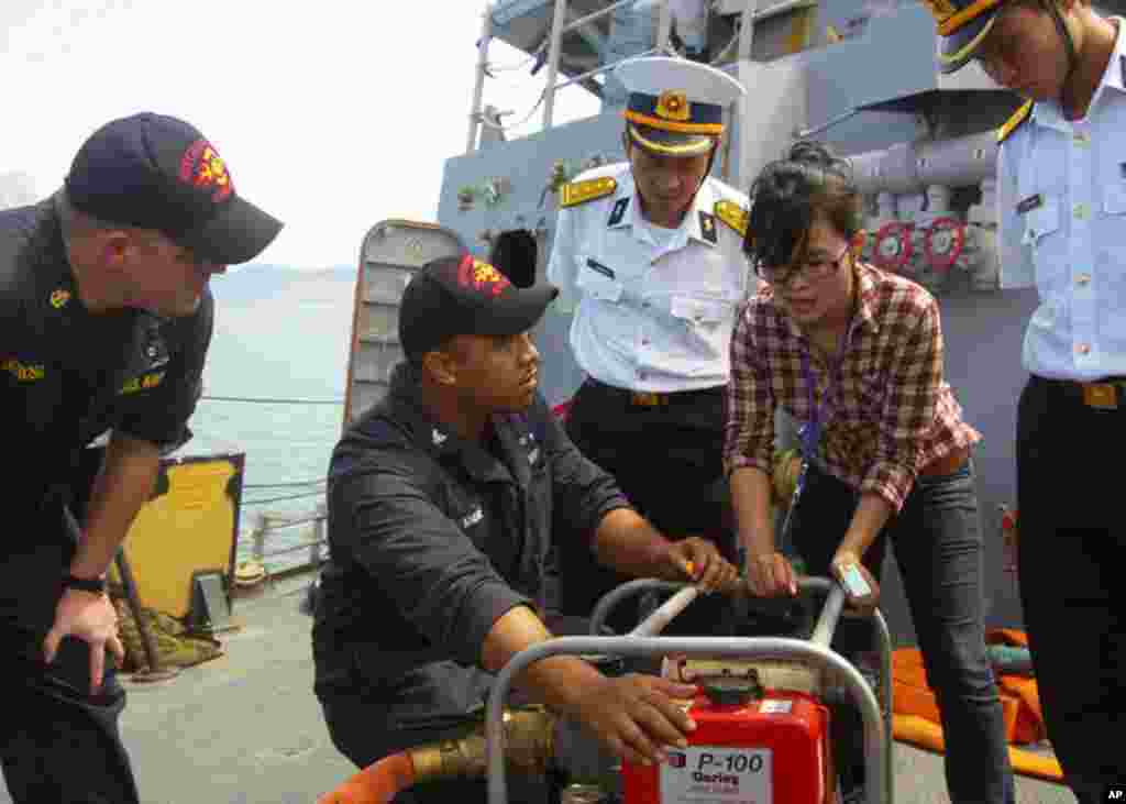 峴港 (7月17日) 鍾雲號損害控制員在訓練項目中通過翻譯向越南海軍官兵解釋P-100型手提水泵的功能。