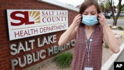 n this Tuesday, May 19, 2020, photo, health investigator Mackenzie Bray adjusts her mask at the Salt Lake County Health Department, in Salt Lake City. (AP Photo/Rick Bowmer)