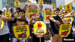 FILE - Protesters wearing snorkels and masks show the thumbs-down sign during a protest rally in front of the Chinese Consular office at the financial district of Makati city, metro Manila, April 10, 2013.