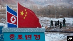 FILE - A Chinese-built fence near a concrete marker depicting the North Korean and Chinese national flags with the words "China North Korea Border" at a crossing in the Chinese border town of Tumen in eastern China's Jilin province. 
