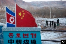 FILE - A Chinese-built fence near a concrete marker depicting the North Korean and Chinese national flags with the words "China North Korea Border" at a crossing in the Chinese border town of Tumen in eastern China's Jilin province.