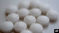 Aspirin pills are arranged on a counter in New York, Aug. 23, 2018. New studies find most people won't benefit from taking daily low-dose aspirin to prevent a first heart attack or stroke. 